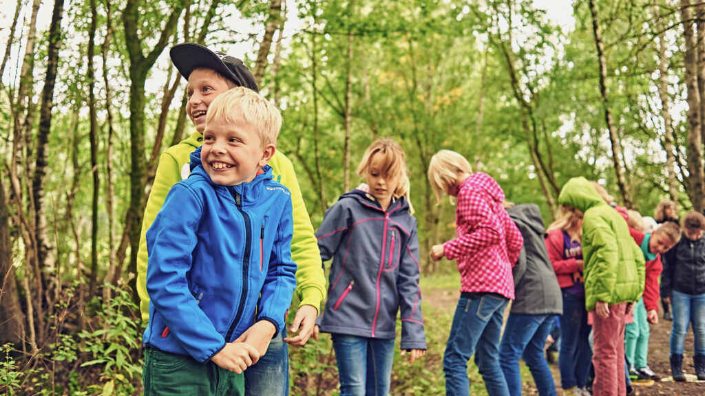 Eine Gruppe Kinder spielt gemeinsam im Wald.