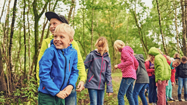 Eine Gruppe Kinder spielt gemeinsam im Wald.