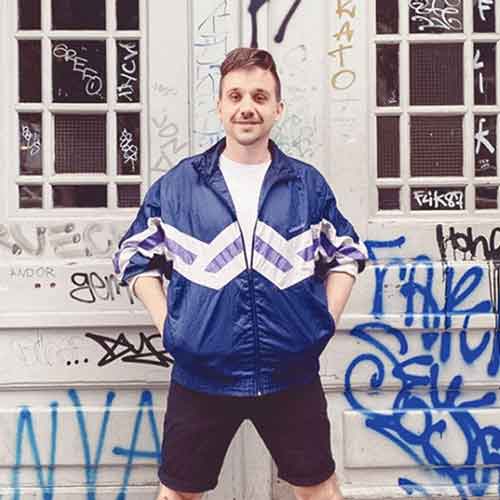 Nico the C steht vor einer Wand mit vielen Graffitis