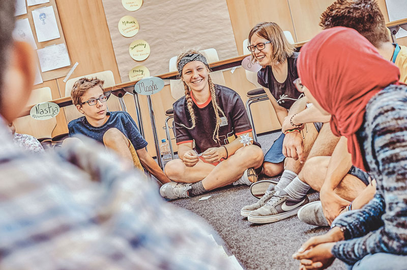 Hier sieht man eine Schulklasse in der Jugendherberge Bielefeld. Sie sitzen im Kreis und scheinen etwas zu diskutieren.
