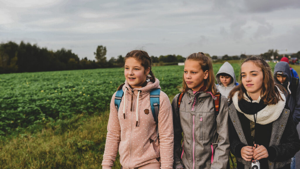 Eine Gruppe von Mädchen wandert an einem Feld entlang